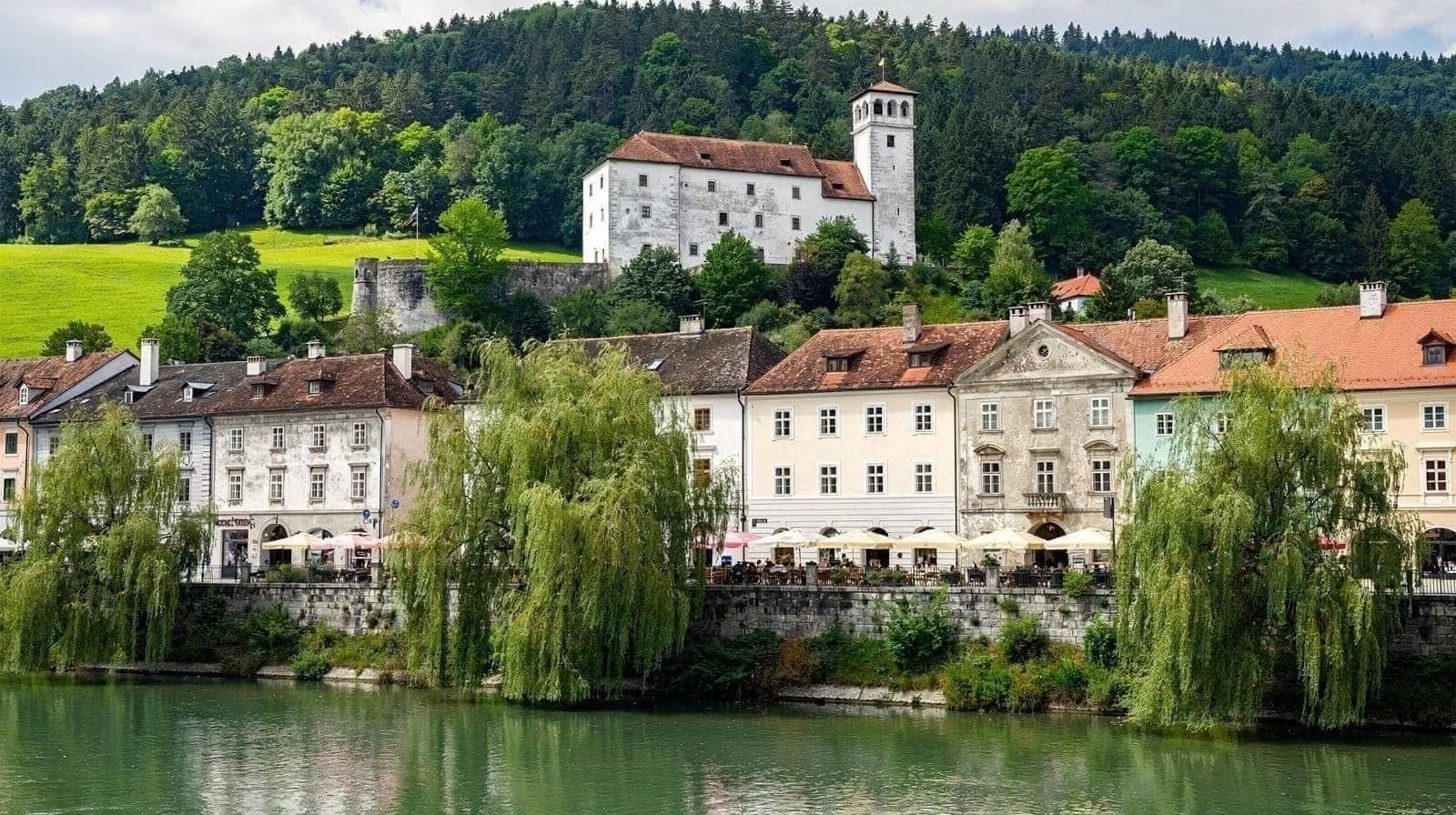 Visitantes alinhados no parapeito da Ponte Tripla, com o Ljubljanica a correr esverdeado sob os arcos de Plečnik.